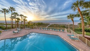 A pool area with lounge chairs and a view of the ocean at sunset. - Beachfront Sky High Views-14th Floor- Sand Key! Resort Level Amenities! (Clearwater)