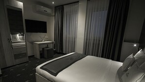 Een hotelkamer met een bed, nachtkastje, spiegel en televisie.
