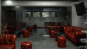 Een modern interieur met leren banken, rode poefs en een glazen scheiding.
