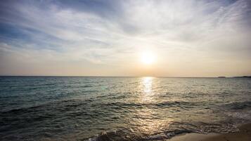 Perto da praia, areia branca, espreguiçadeiras, guarda-sóis
