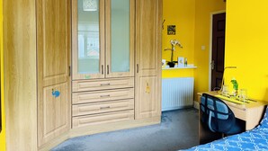 Ein Zimmer mit einem Holzschrank, einem Schreibtisch und einem Bett.