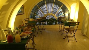 A dining area with a high arched window, wooden flooring, and tables set for a meal. - B&B Turin Très Chic. In the historic center with its own entrance (Torino)