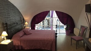 A bedroom with a bed, a nightstand, a chair, a desk, a potted plant, and a view of the outside. - B&B Turin Très Chic. In the historic center with its own entrance (Torino)
