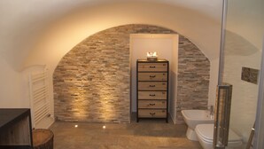 A bathroom with a stone wall, a wooden cabinet with drawers, a bidet, and a toilet. - B&B Turin Très Chic. In the historic center with its own entrance (Torino)