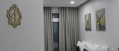 Une chambre d’hôtel avec un lit, des rideaux, une fenêtre et deux tableaux accrochés au mur.