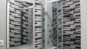 A modern shower with a glass enclosure and a tiled wall with a geometric pattern. - Bella Gaia (Vila Nova de Gaia)