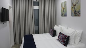 A hotel room with a bed, curtains, a television, and two paintings on the wall. - Bella Gaia (Vila Nova de Gaia)