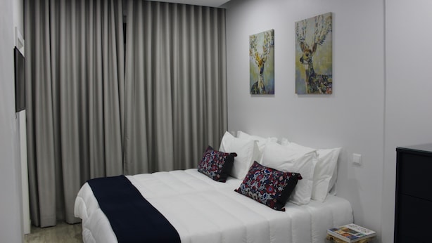 A hotel room with a large bed, two pillows, a bedside table with a book, and a painting on the wall. - Bella Gaia (Vila Nova de Gaia)