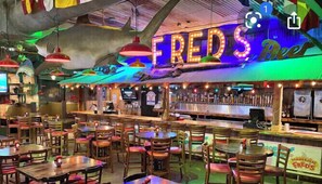 Enjoy a casual dining experience at FRED'S Beer, where wooden tables and chairs are arranged in a spacious layout.