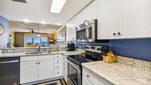 A modern kitchen with white cabinets, a stainless steel microwave, and a black oven. - Seacrest 703 is a 2 BR Gulf Front on Okaloosa Island by RedAwning (Fort Walton Beach)