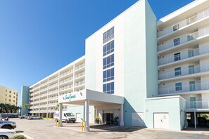 A multi-story hotel with a central entrance, a parking area, and a FedEx delivery truck. - Seacrest 605 is a 2 BR Gulf Front on Okaloosa Island by RedAwning (Fort Walton Beach)