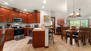 A kitchen with wooden cabinets, a stainless steel oven, and a dining area with a table and chairs.