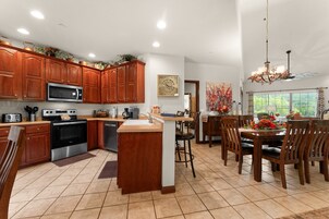 A kitchen with wooden cabinets, a stainless steel oven, and a dining area with a table and chairs.