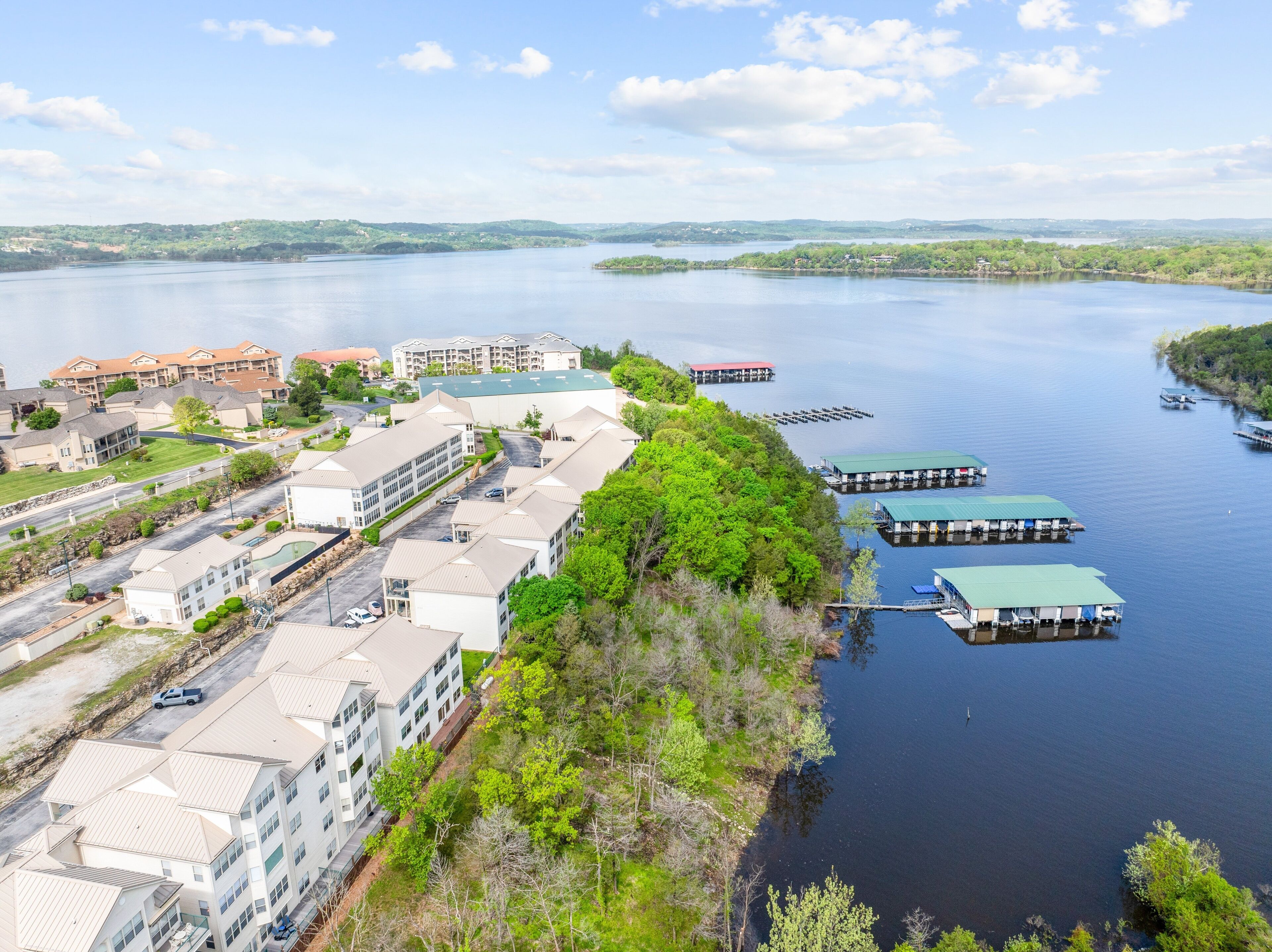 A lakeside hotel with multiple buildings, docked boats, and a clear view of the lake.