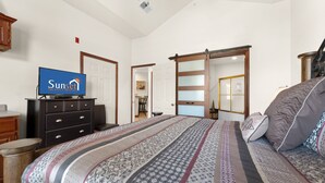 A bedroom with a bed, a dresser, a television, and a sliding door.