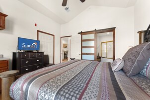 Un dormitorio con cama, cómoda, televisor y puerta corrediza.