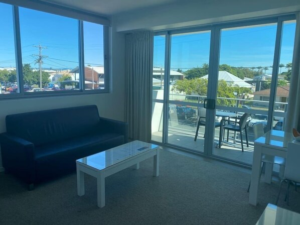 Enjoy a spacious living room with a large window offering a clear view of the outside, a comfortable sofa, and a dining area with a table and chairs.
