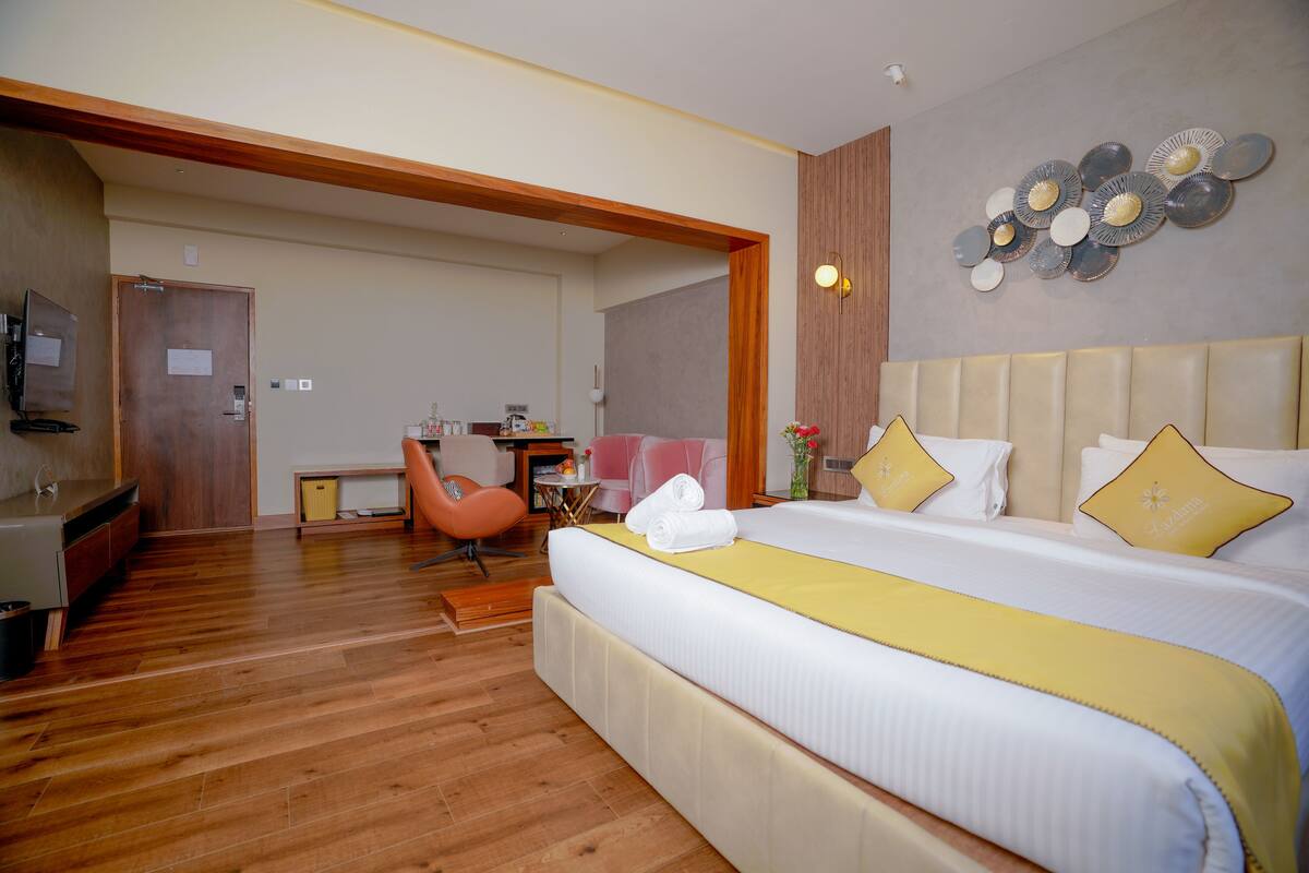 A hotel room with a large bed, a desk, a chair, and a television.