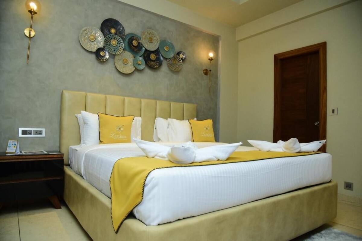 A hotel room with a large bed, a nightstand, a wall-mounted decorative plate arrangement, and a wooden door.