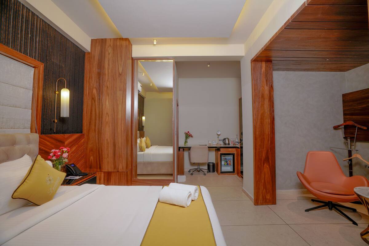 A hotel room with a bed, a desk, a chair, and a small kitchenette.