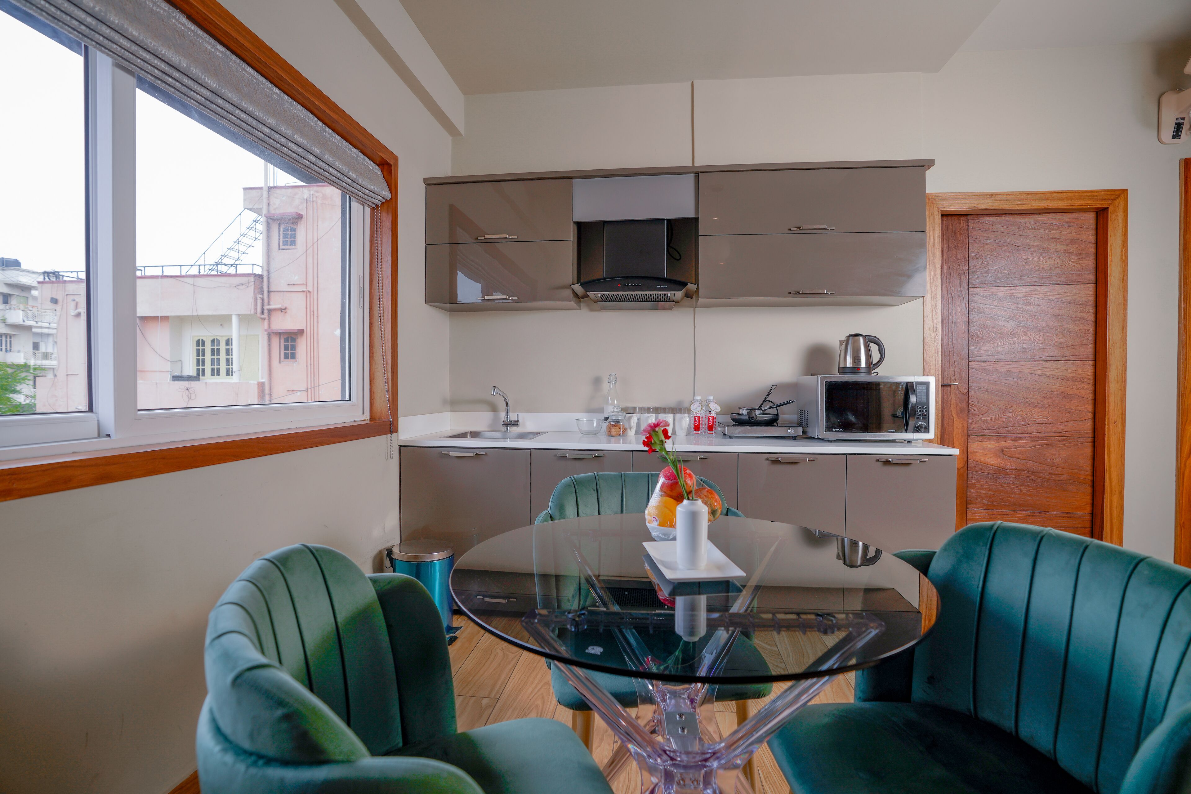 Une cuisine moderne avec une table à manger en verre et des chaises recouvertes d’un tissu vert.