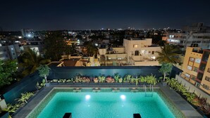 A rooftop pool with a view of a cityscape at night. - Lazdana Hotel Bangalore (Bengaluru)