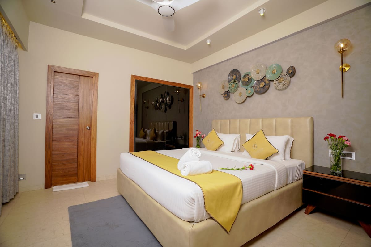 A well-lit bedroom with a large bed, a wooden door, and a wall decorated with circular plates.
