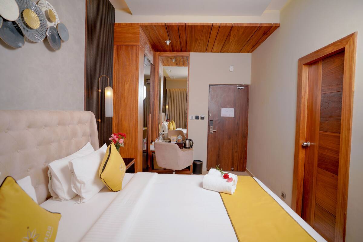 A hotel room with a bed, bedside table, and a mirror.