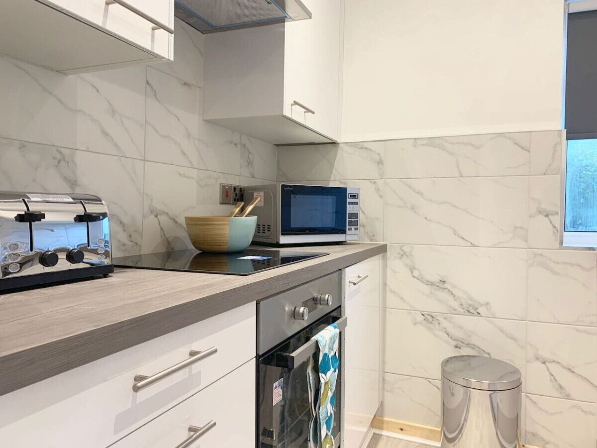 A modern kitchen with a marble backsplash, a built-in microwave, a toaster, and a stainless steel oven.