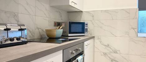 A modern kitchen with a marble backsplash, a built-in microwave, a toaster, and a stainless steel oven.