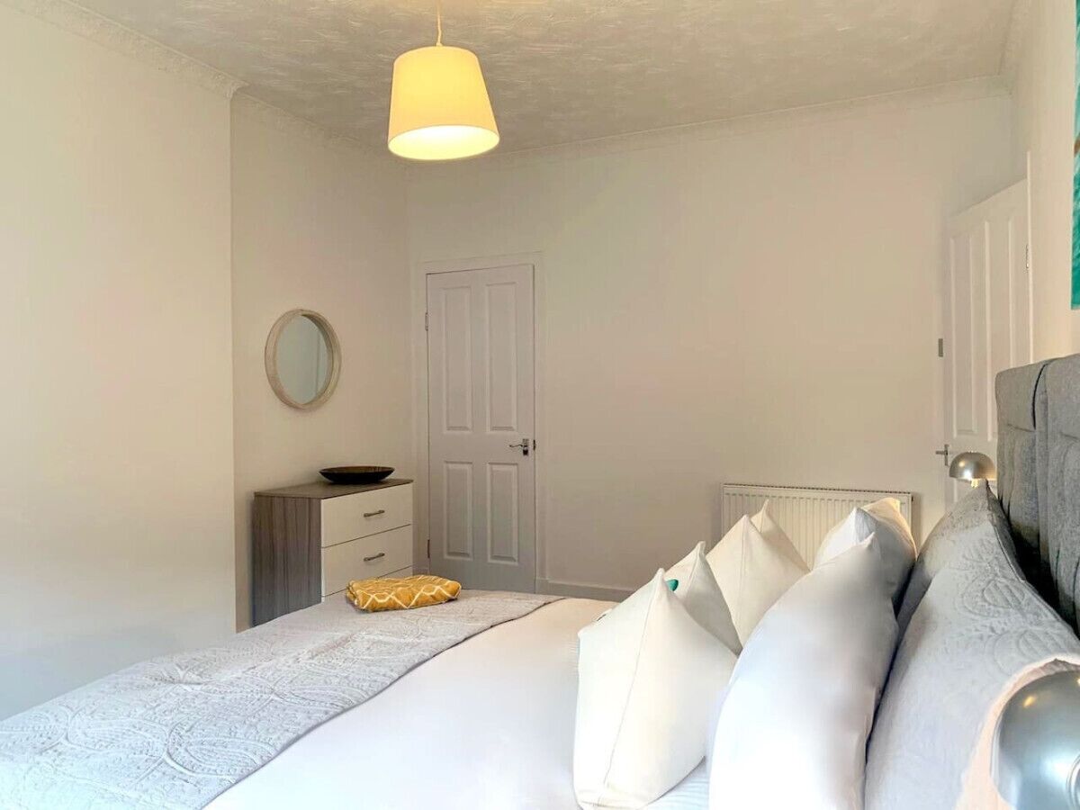 Un dormitorio con cama, mesita de noche, cómoda y una puerta.