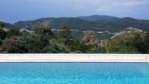 A swimming pool with clear blue water, surrounded by lush greenery and mountains in the background. - Fig Tree Villa, private pool & whirl pool, seclusion, privacy, spectacular views (Marmaris)
