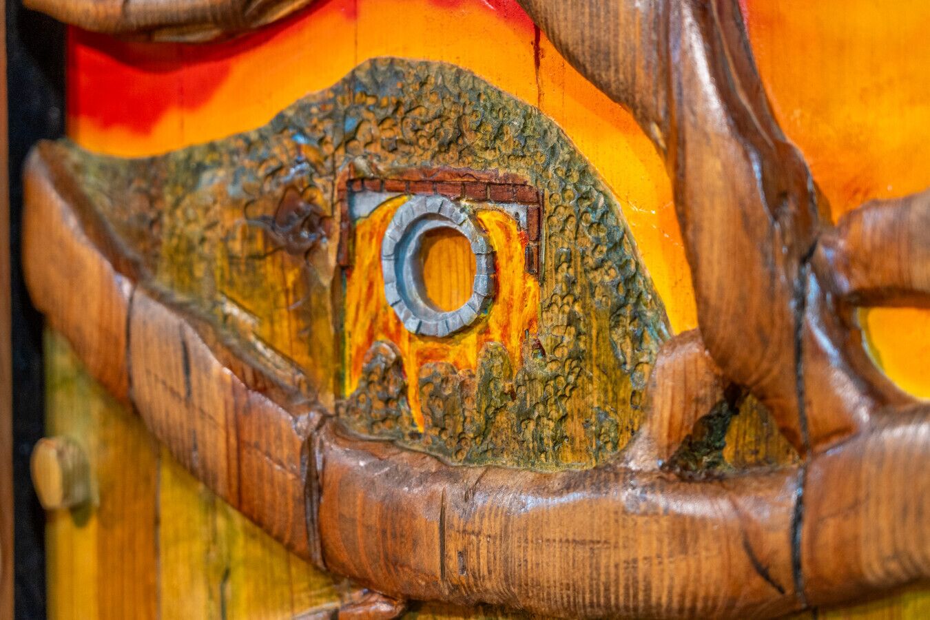 Un gros plan d’une structure en bois ornée de sculptures complexes et d’un anneau métallique.