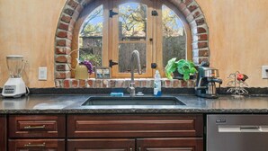 A kitchen with a brick arch above the sink, a built-in coffee maker, and a blender on the counter. - The Hobbit House, Fantasy comes Home! (Russellville)