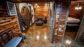 A narrow hallway with wooden walls and a polished concrete floor. There is a bench on the left and a bed on the right. - The Hobbit House, Fantasy comes Home! (Russellville)