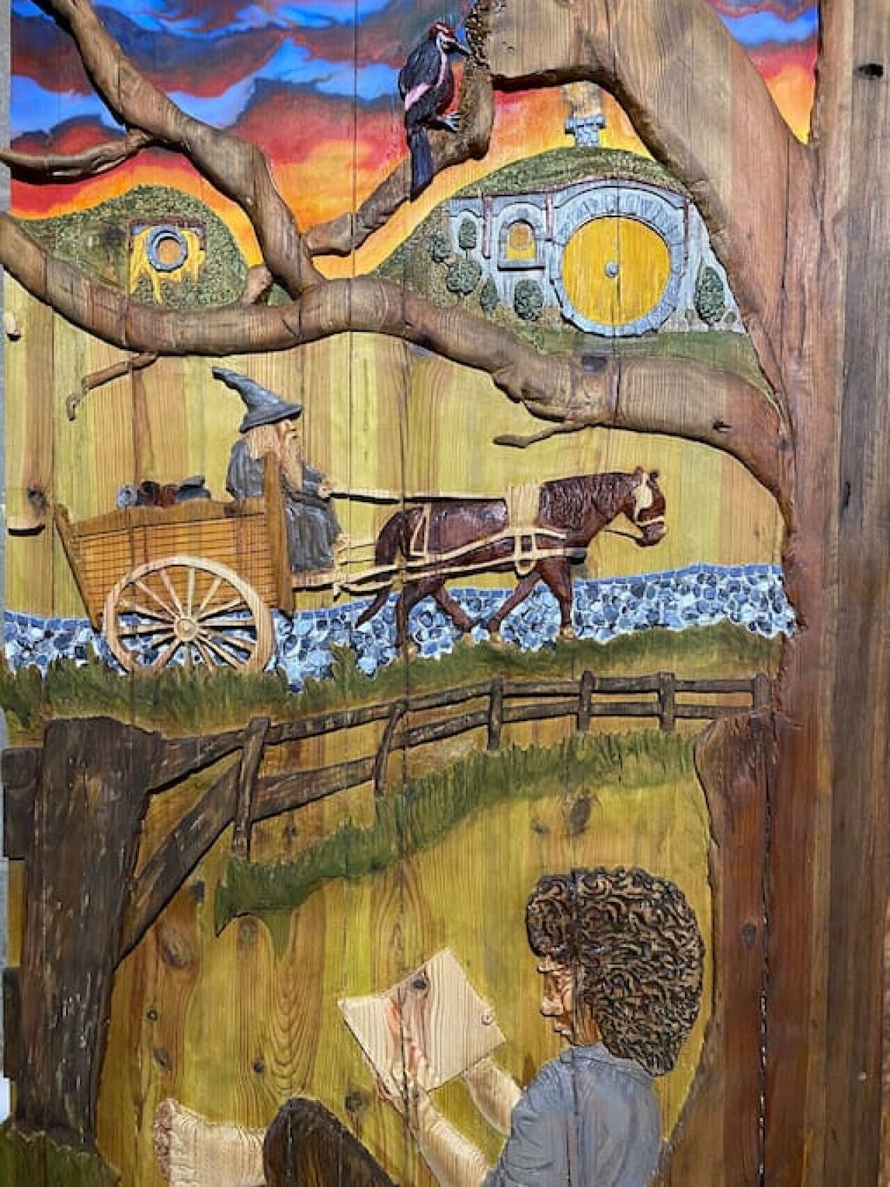 Un mural que muestra a una persona leyendo, un caballo, un carro y un árbol.