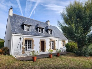 A two-story house with a sloped roof, white exterior walls, and a front porch with outdoor seating. - TUMULUS - Holiday home for rent in Carnac - S23 (Carnac)