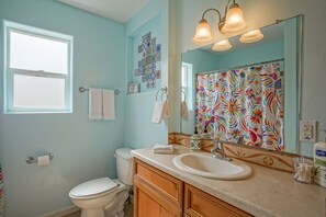 A bathroom with a toilet, sink, and a mirror with a colorful floral shower curtain. - Walk2Old Town, 2bd/1ba, Large Yard, Pet Friendly! (Albuquerque)