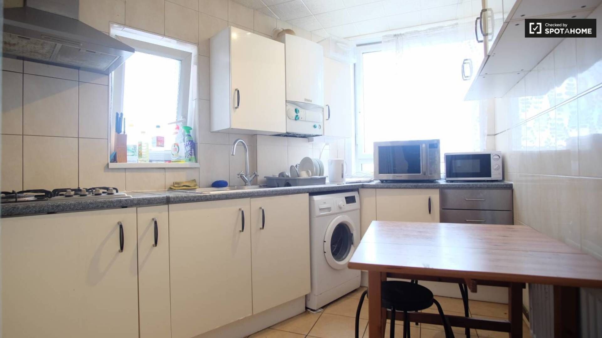 A compact kitchen with a washing machine, microwave, and sink.