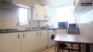 A compact kitchen with a washing machine, microwave, and sink. - 2-bed Apartment in London Woolwich (London)