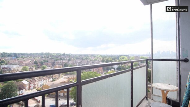 A balcony with a view of a cityscape, a small table, and a chair. - 2-bed Apartment in London Woolwich (London)