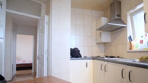 A kitchen with white cabinets, a wooden countertop, and a window with kitchen utensils. - 2-bed Apartment in London Woolwich (London)