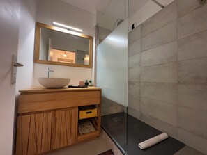 Een bad/douchecombinatie, een haardroger, handdoeken, toiletpapier