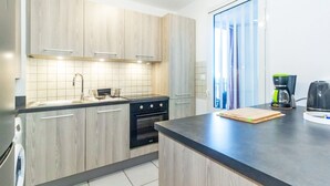 Een moderne keuken met lichte houten kastjes, een zwarte kookplaat en een koffiezetapparaat op het aanrecht.
