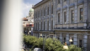 A historic building with a classical architectural style, featuring arched windows and a prominent dome in the background.