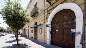 A street with a building featuring large brown doors and a tree in front.