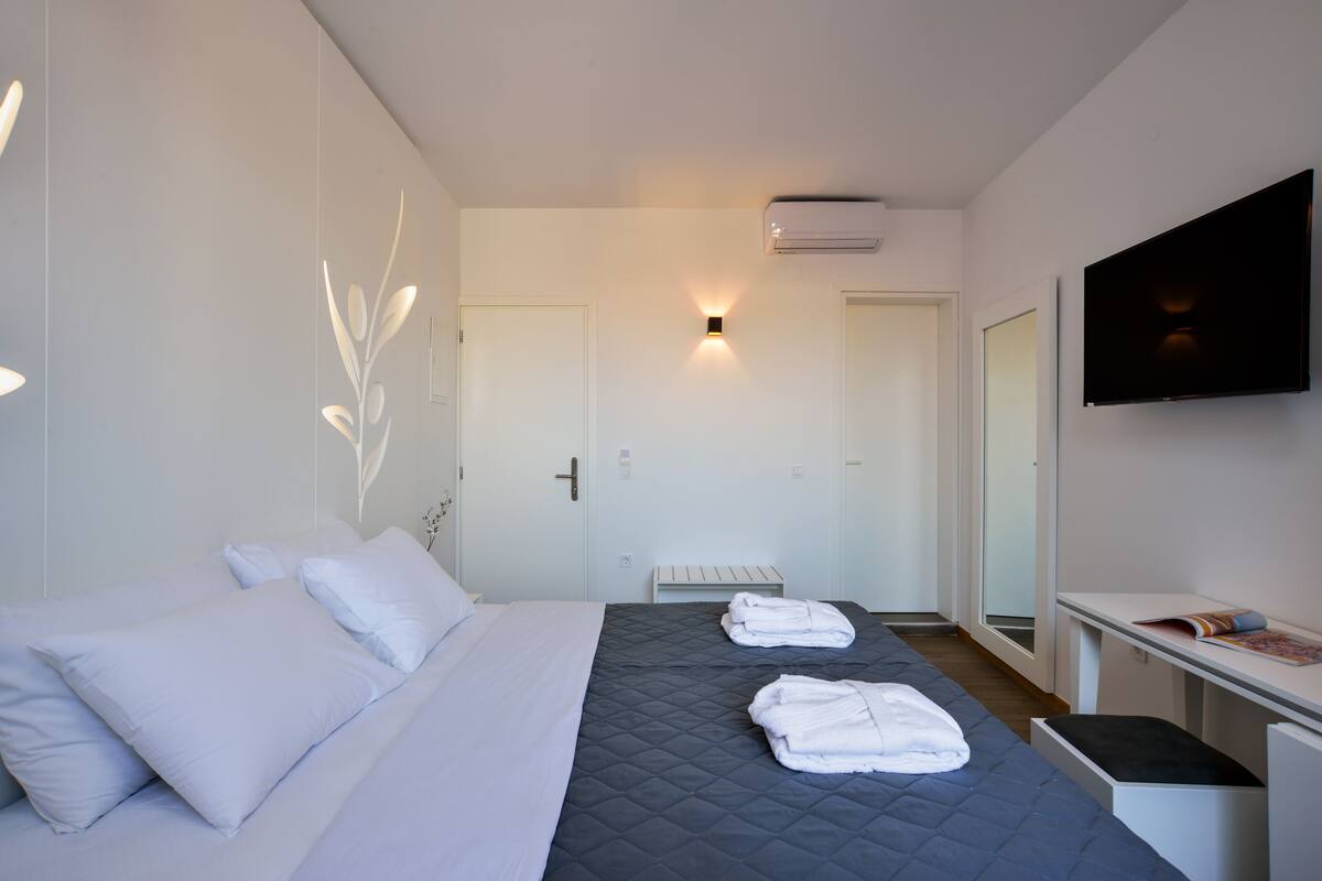 Een hotelkamer met een bed, nachtkastje, televisie en een wandairconditioner.