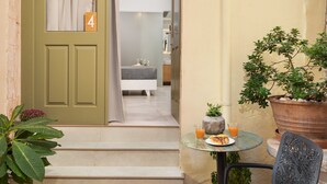 A small outdoor seating area with a table, chair, and potted plants. - Elia Portou Luxury Residence (Chania)