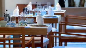 A dining area with wooden tables and chairs, neatly set with plates, glasses, and napkins. - Elia Portou Luxury Residence (Chania)