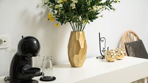 A white countertop with a coffee maker, a vase with flowers, and decorative items. - Elia Portou Luxury Residence (Chania)